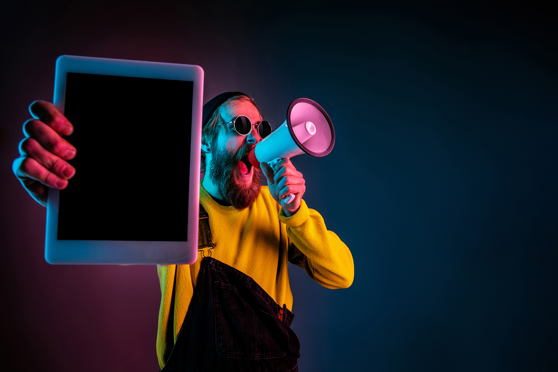 Rapaz com megafone mostrando um tablet com fundo preto. Demonstra a falta de um site.
